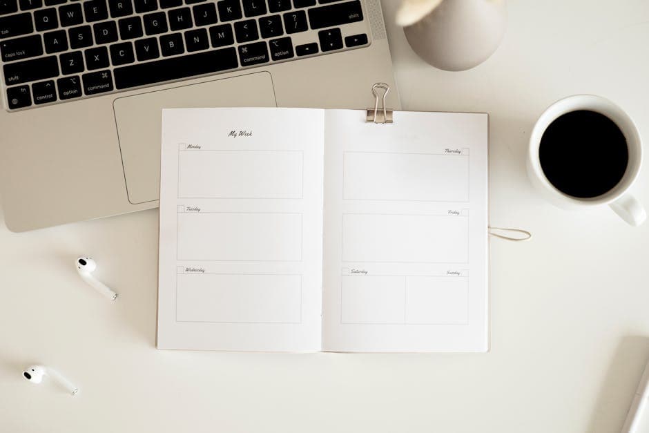 Overhead view of a desk with planner, coffee, laptop, and earbuds in a minimalist style.